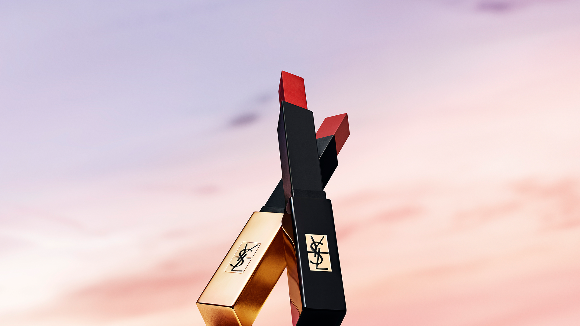 Photography of two YSL red lipsticks - the slim and the slim velvet fallin down in a sunset pinky sky